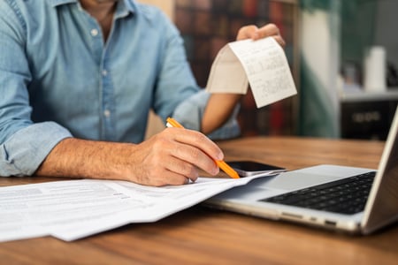 Business owner reconciling invoices on laptop – bookkeeping services
