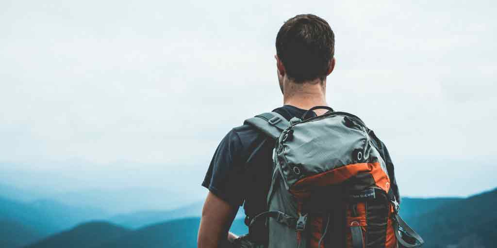 Hiker with a backpack looking out over misty mountains