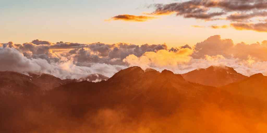 Sunset over mountain peaks above the clouds