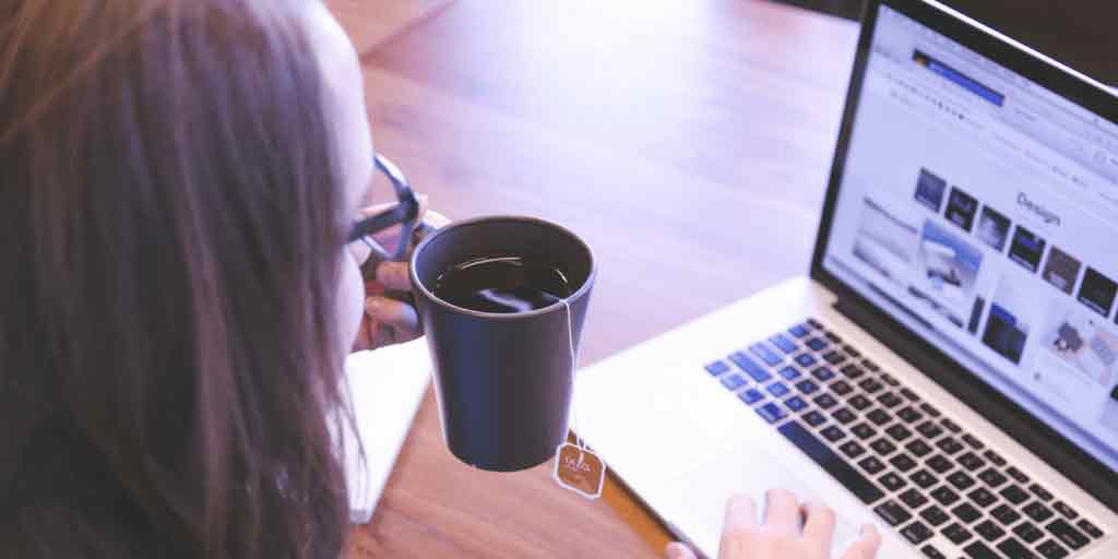 Person with a cup of tea working on a laptop