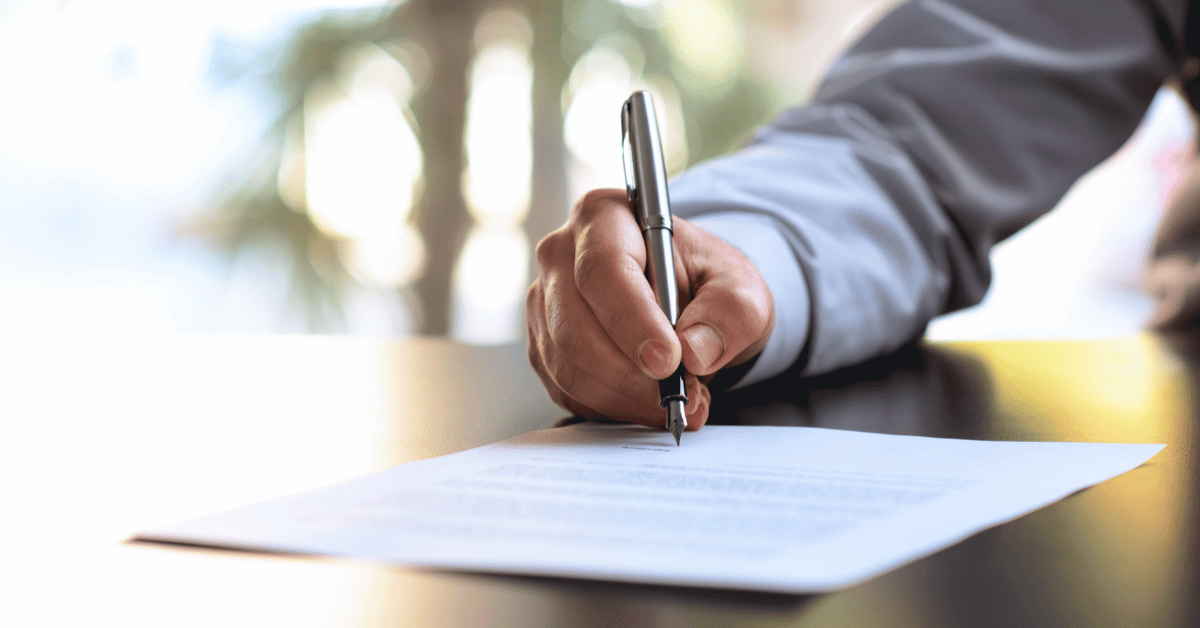 image of a man holding a fountain pen signing a document