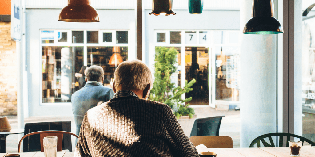 Two men sitting in a sunlit cafe