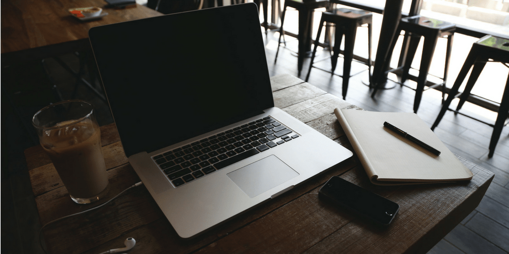 Laptop, notebook, phone and iced coffee on a cafe table