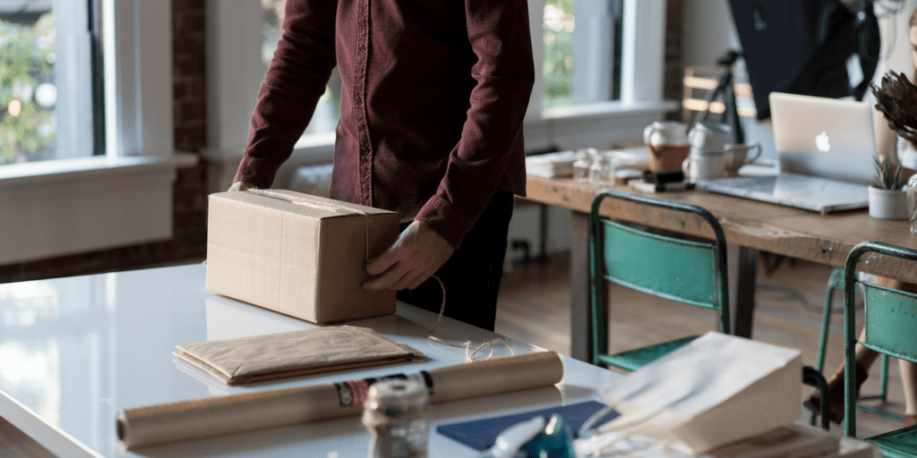 Small business owner packing a shipping box in a studio