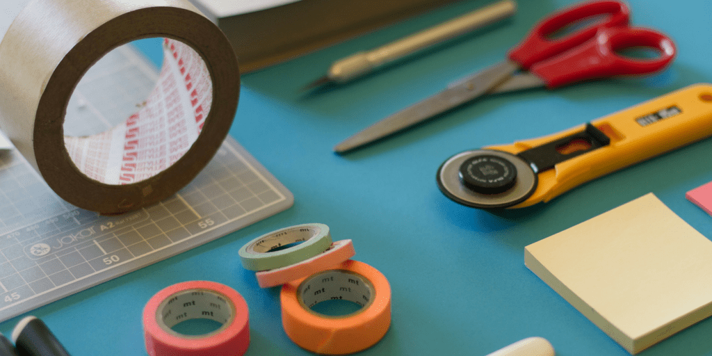 Packing tape, scissors and craft supplies on a blue desk