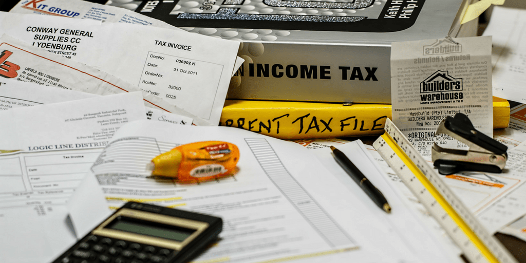 pile of invoices, receipts, a calculator, and 2 tax books
