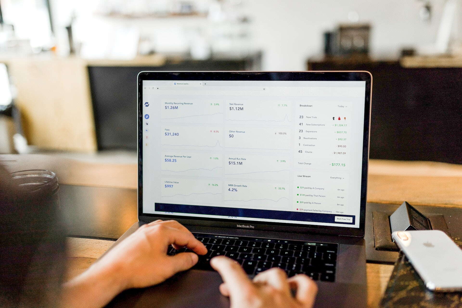 looking over the shoulder of someone on a laptop and a screen of numbers