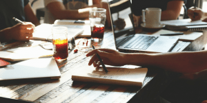 table with laptops, papers, and drinks 