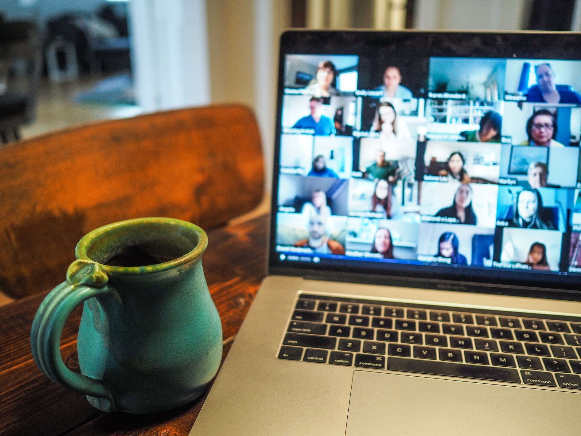 image of a mug and an online meeting with lots of boxes of people's faces on a laptop 