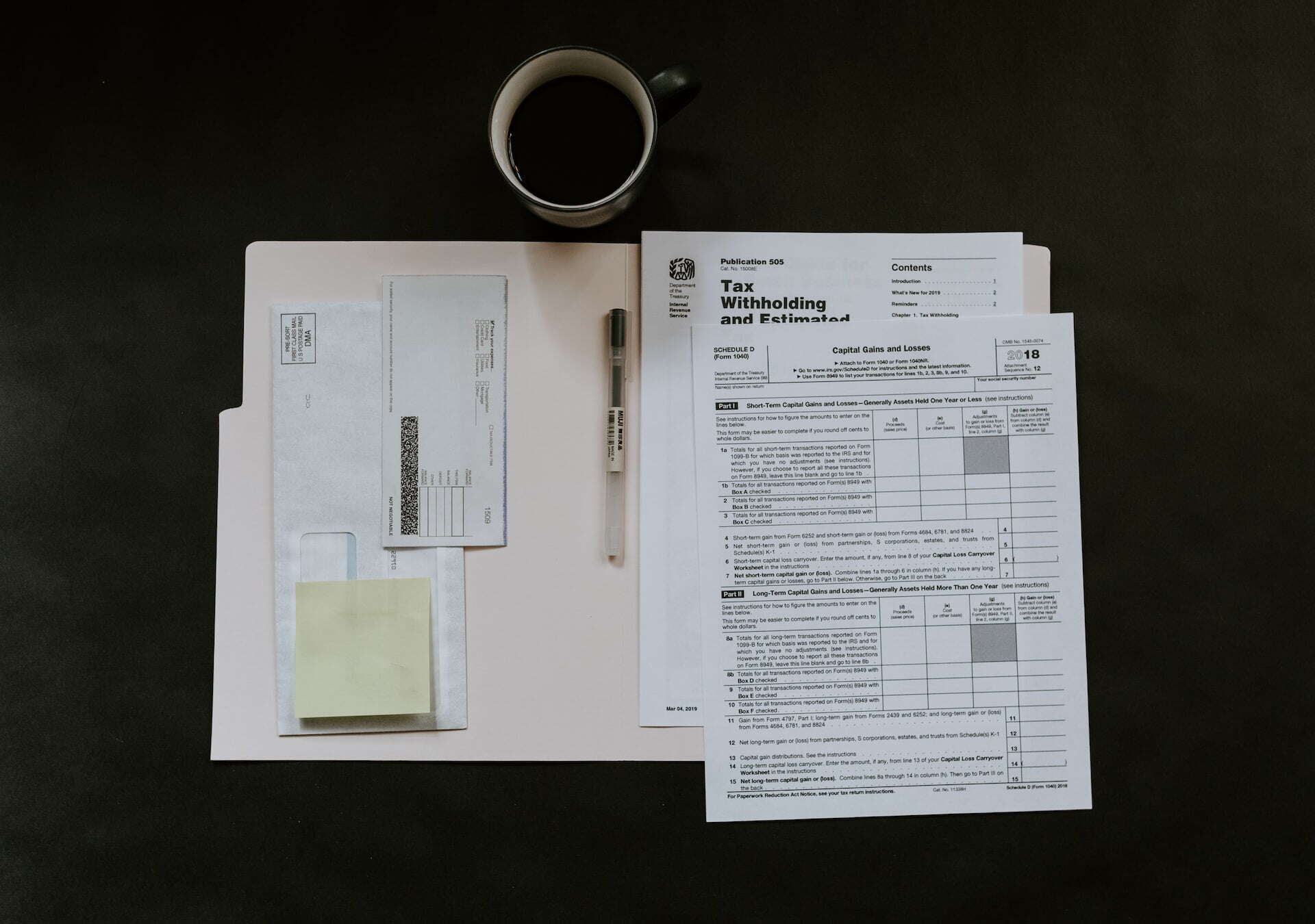 a paper file full of tax documents laid out with a checkbook and coffee on the table 