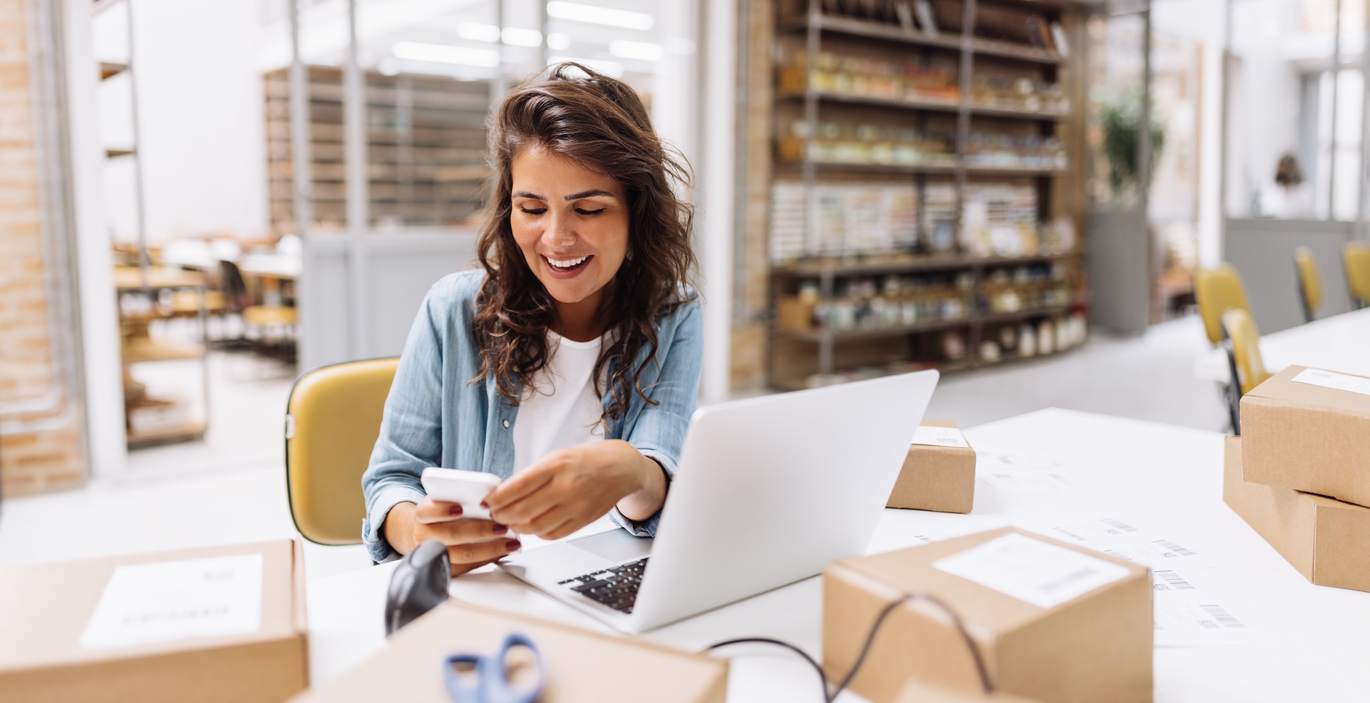 Small business owner managing orders with a laptop and phone—illustrating the benefits of outsourced accounting services for e-commerce and growing companies.