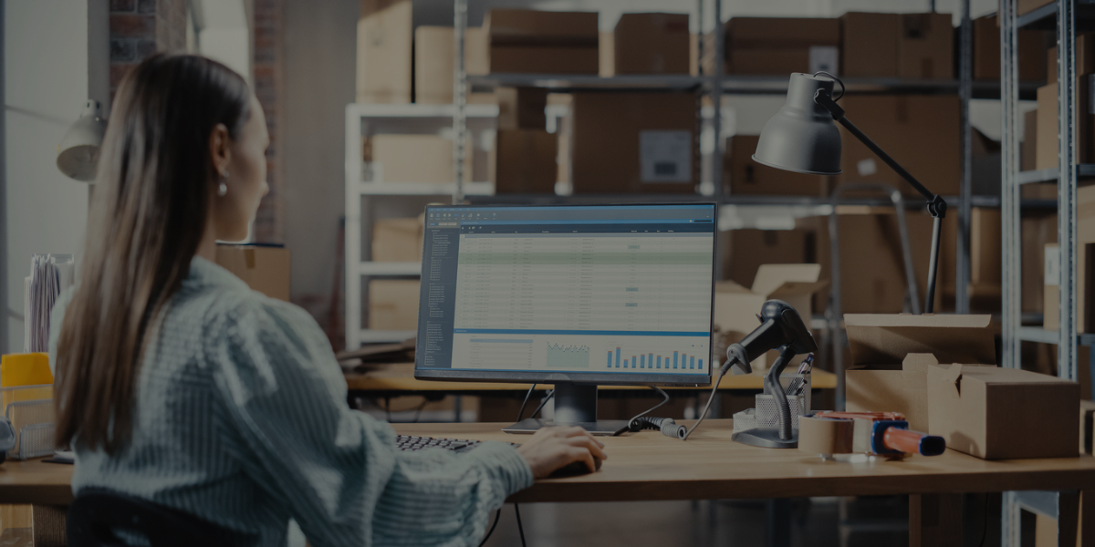 Small business owner reviewing financial data and inventory charts on a computer monitor during month-end close.