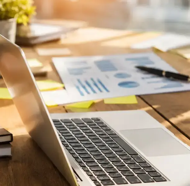 Sunlit desk with laptop and financial reports, showcasing organized accounting and CFO services for local businesses.
