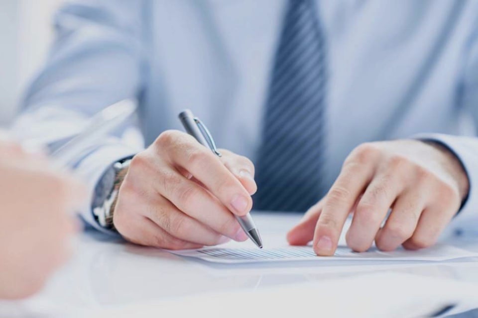 Professional reviewing and signing financial documents, representing the CFO and controller roles.