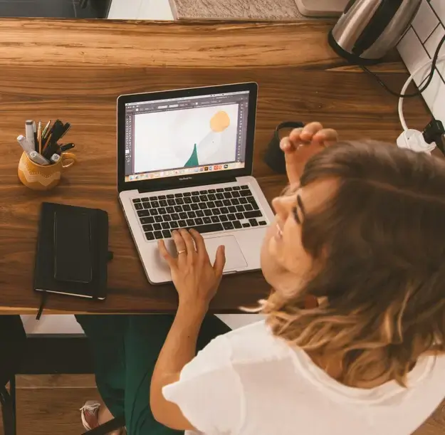 Creative professional designing on a laptop, benefiting from clear project profitability and margin tracking.