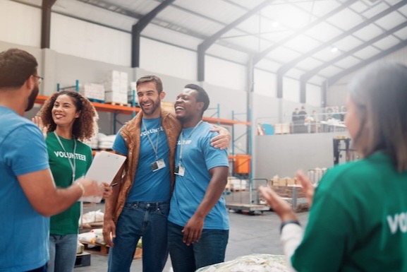 Nonprofit volunteer team celebrating together in a donation warehouse.