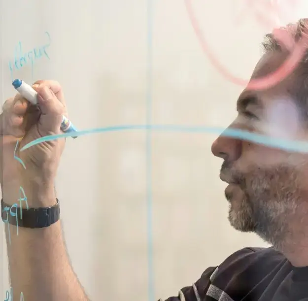 Business leader mapping out strategic financial growth and cash flow plans on a glass whiteboard.